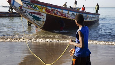 A Senegalese fisher helps guide a boat ashore.
